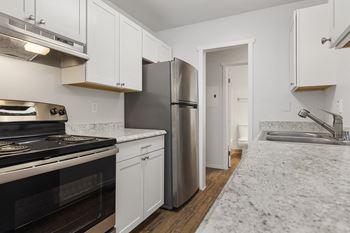 A kitchen with white cabinets and a stainless steel refrigerator.